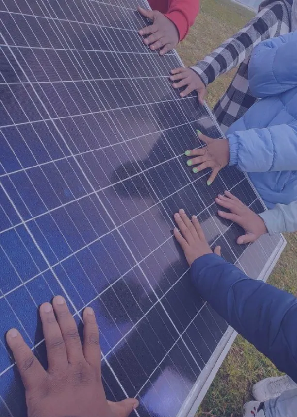 Children's hands resting on a solar panel during a community visit